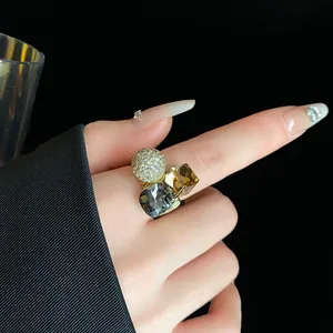 Close-up of a gold-plated geometric open ring featuring sparkling crystals and zircon