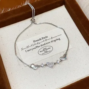 Detailed view of a silver heart charm bracelet with sparkling zircon stone accents