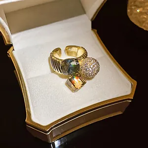 Macro view of gold plated open ring with grey and amber zircons and sparkling pavé sphere detail.