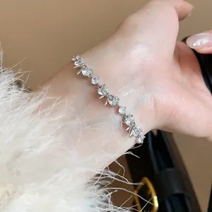 Elegant silver bracelet with sparkling zircon bow and flower charms worn on a female wrist