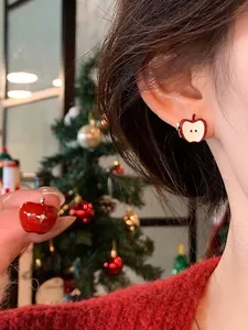Detalle de bonitos pendientes de botón con forma de manzana roja sobre fondo de Navidad