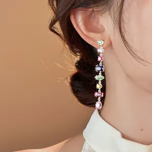 Close-up detail of colorful irregular zircon tassel earrings worn by a model's ear.