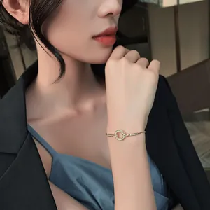 Vista detallada de una elegante pulsera dorada con un dije circular de micro diamantes.