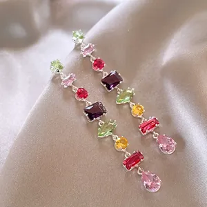 Detailed macro shot of vibrant multi-colored zircon tassel earrings on silk