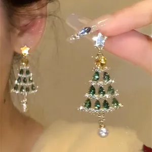 Detalle de pendientes de árbol de Navidad con piedras verdes brillantes y perlas.