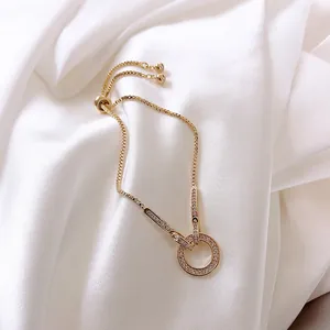 Primer plano de una pulsera dorada ajustable con un anillo pavé de cristales