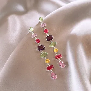 Exquisite close-up of colorful irregular zircon tassel earrings on elegant satin fabric