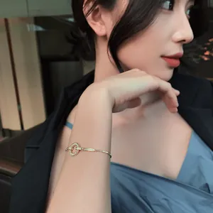 Elegante pulsera de oro con dije circular de diamantes micro-pave en la muñeca de modelo