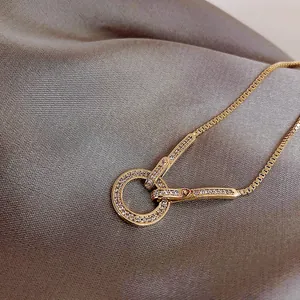 Primer plano de una elegante pulsera dorada con colgante de círculo de diamantes sobre seda.
