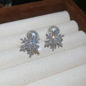 Primer plano de pendientes de copo de nieve brillantes con perlas blancas elegantes