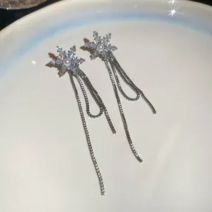 Primer plano de pendientes de copo de nieve con pedrería brillante y una fina perla