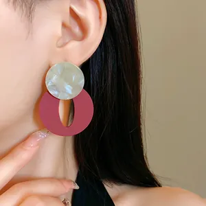 Close-up detail of retro acrylic geometric stud earrings in wine red and marble white