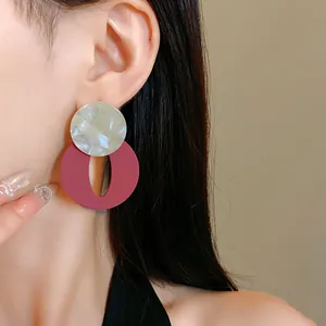 Close-up view of vintage acrylic round and oval geometric dangle earrings worn by a model