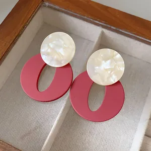 Detailed view of retro acrylic round and oval stud earrings in red and cream marbling
