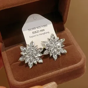 Detailed close-up of sparkling flower-shaped stud earrings with marquise crystals in a box.