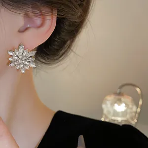 Detailed close-up of elegant silver needle sparkling crystal flower stud earrings on model