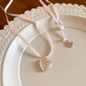 Detailed view of silver heart pendant on pink ribbon necklace with pearl and star