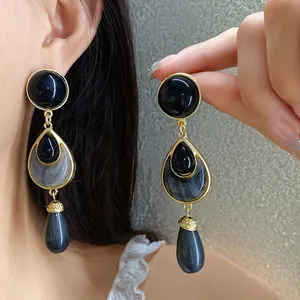 Vintage gold-toned drop earrings featuring elegant black and grey marbled stone pendants