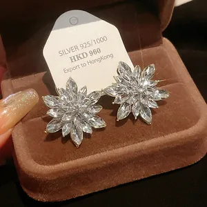 Close-up view of sparkling flower-shaped rhinestone stud earrings set in a brown velvet box