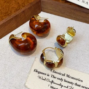 Vue détaillée de boucles d'oreilles créoles vintage en résine ambrée avec de l'or
