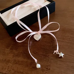 Detailed view of pink ribbon necklace with silver heart locket, pearl and star charm