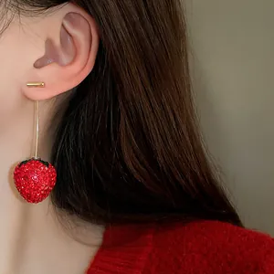 Detailed macro shot of sweet red rhinestone strawberry drop earrings worn by a model