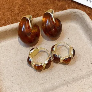Gros plan de boucles d'oreilles vintage en résine ambrée avec détails dorés style automne