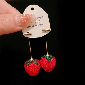 Detailed macro shot of sparkling red rhinestone strawberry earrings on white card