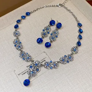 Close-up of vintage French jewelry set with blue rhinestone flowers and round gems.