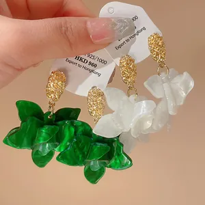Detailed view of handmade green and white resin flower earrings with silver needles.