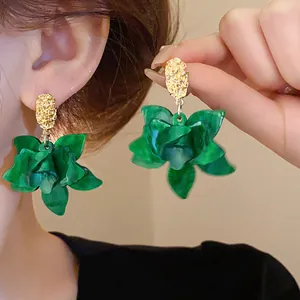 Elegant green petal flower earrings with gold textured tops shown on a model's ear