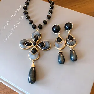 Vintage floral pendant necklace and drop earrings set on a grey book background
