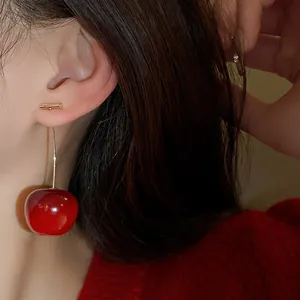Detailed close-up showing the glossy red texture of a sweet cherry dangle earring on an ear