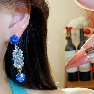 Close-up of French vintage floral dangle earrings with blue crystals and diamonds.