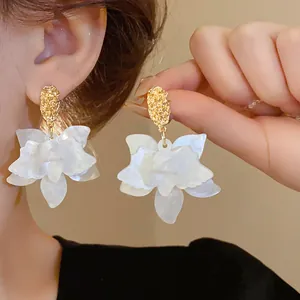 Detailed view of elegant white multi-layered flower earrings with textured gold studs.