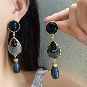 Vintage style drop earrings featuring black and grey resin stones with gold-tone frames