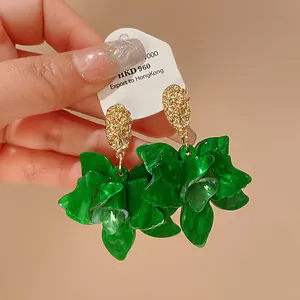 Close-up detail of stylish green resin flower earrings featuring gold textured stud design