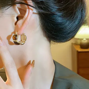 Gros plan détaillé d'une boucle d'oreille créole en résine dorée vintage avec pierres ambrées.