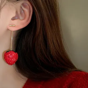 Close-up view of elegant rhinestone-encrusted red strawberry drop earrings on an Asian model