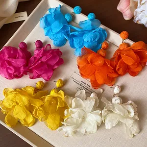 Primo piano di orecchini colorati a forma di fiore in rafia e chiffon su un vassoio