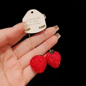 Close-up of sparkling red strawberry rhinestone earrings on a display card
