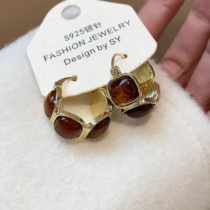 Gros plan de boucles d'oreilles rétro en résine avec finition dorée et ambre.