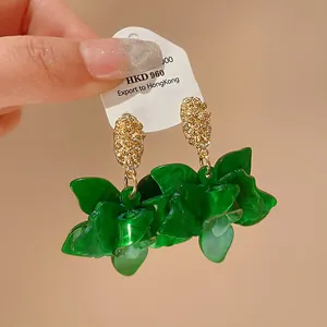 Close-up detail of green resin floral dangle earrings with textured gold-tone metal studs