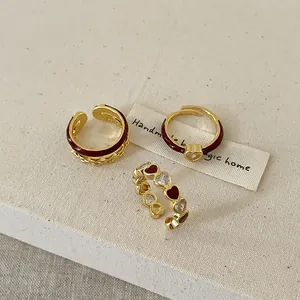 Vue détaillée de trois bagues dorées ajustables avec motifs de cœurs en émail rouge