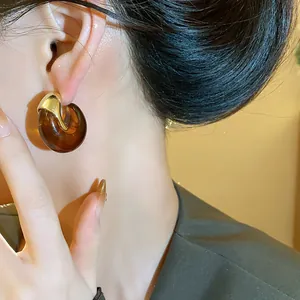 Gros plan sur une créole vintage en résine ambre avec accent doré sur l'oreille