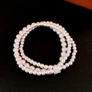 Detail of elegant multi-layer pearl bracelet with a sparkling crystal-encrusted clasp.
