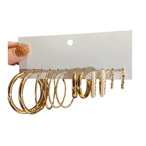Set mit 6 Paar stilvollen goldenen Creolen und Perlenohrringen auf Displaykarte