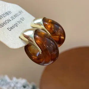 Gros plan sur des boucles d'oreilles en résine ambrée avec clous en argent S925.