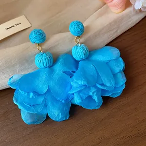 Dettaglio orecchini a fiore in chiffon blu con borchie in rafia