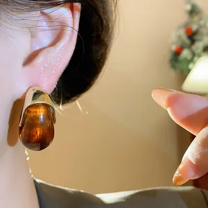 Détail rapproché de boucles d'oreilles rétro en résine ambrée avec tiges en argent